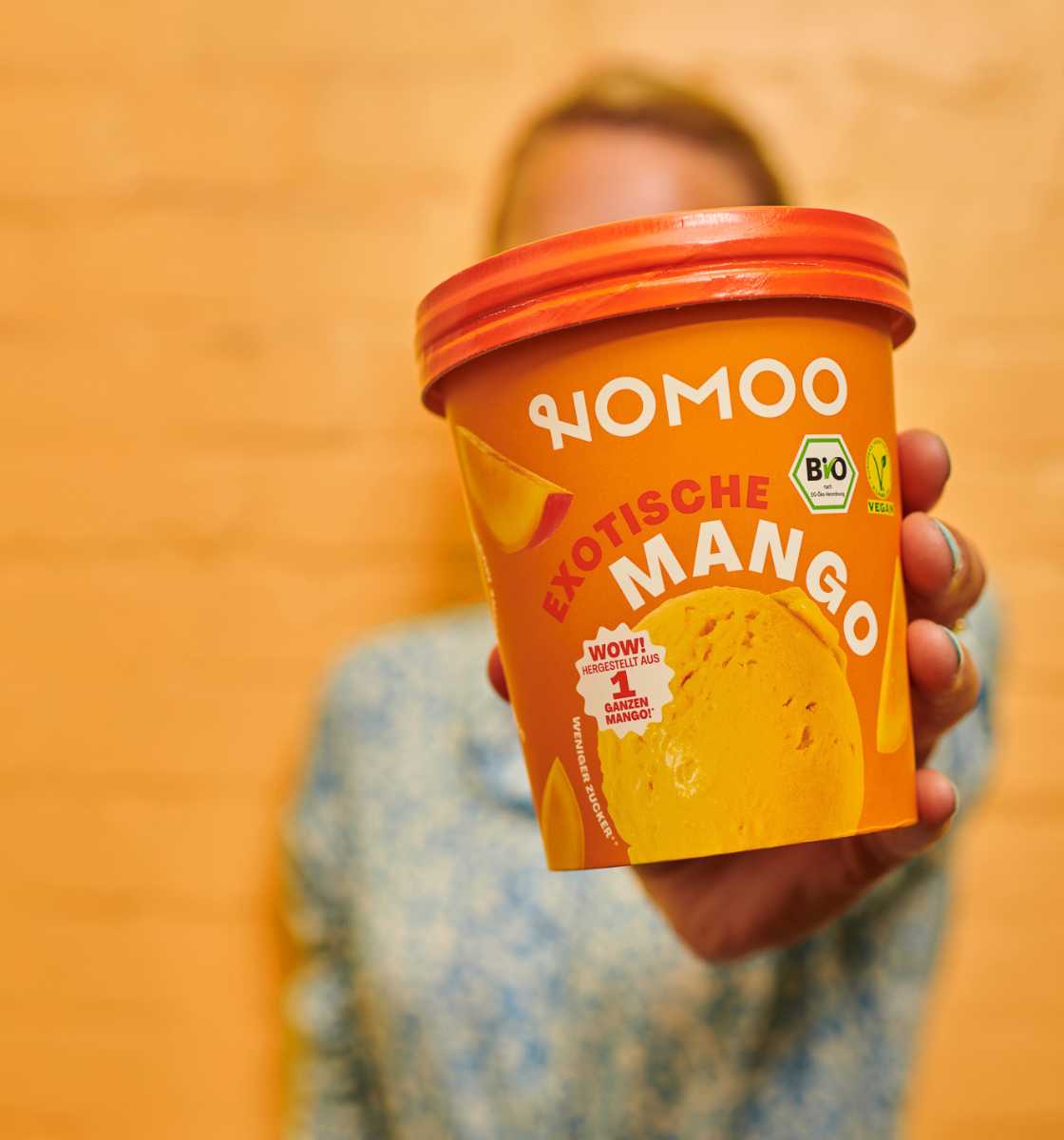 Frau hält Mangoeis von NOMOO in die Kamera